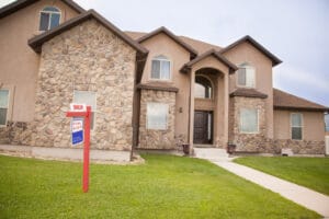 A real estate for sale sign with a sold rider in front of a home