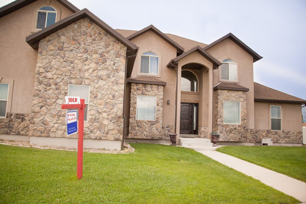 A real estate for sale sign with a sold rider in front of a home