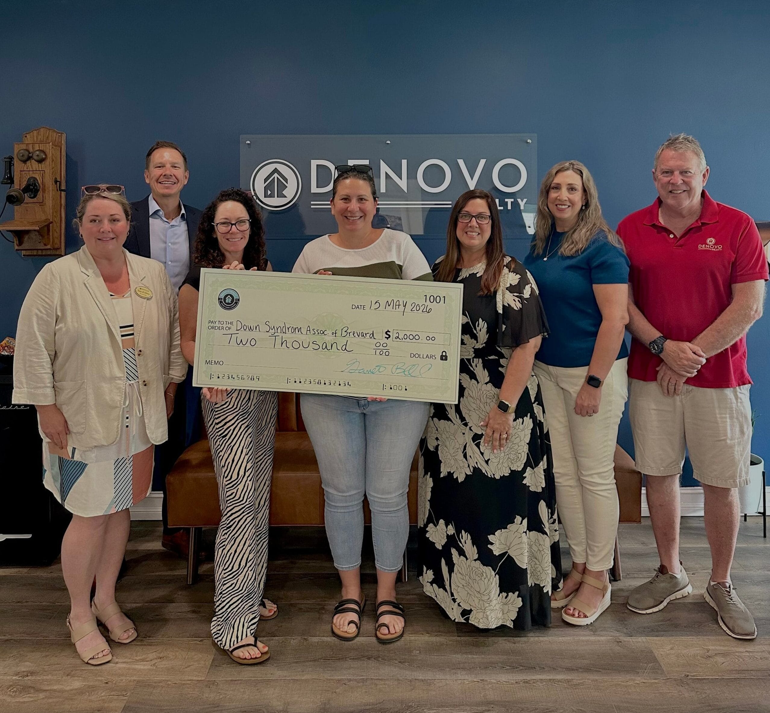 Denovo Realty team presenting a donation to a local organization